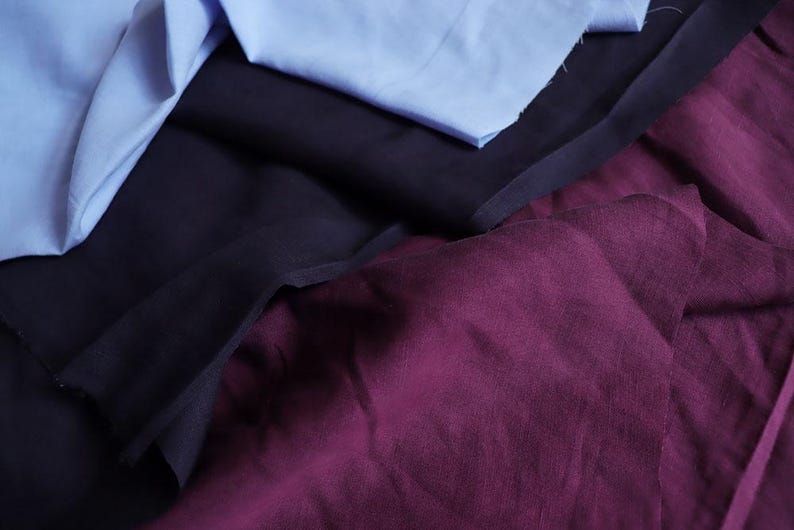 May include: An assortment of fabric swatches in shades of blue, navy, and burgundy. The fabrics are layered and crumpled, showcasing their textures and colors. Ideal for textile projects or design inspiration.