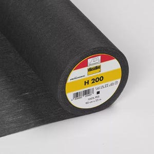 Könnte beinhalten: Eine Rolle schwarzes Gewebe mit einem gelb-weißen Etikett. Das Etikett trägt die Aufschrift "Vlieseline H 200" und enthält einen Barcode sowie die Maße 90 cm x 25 m. Der Stoff ist dunkelgrau.