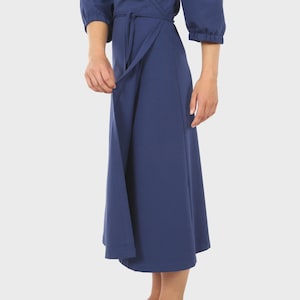 May include: A navy blue wrap dress with three-quarter sleeves and a tie waist. The dress has a midi-length skirt and is made of a smooth, solid fabric. The sleeves are gathered at the cuffs.