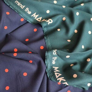 K&ouml;nnte beinhalten: Zwei Stoffe mit Polka-Dot-Muster. Einer ist marineblau mit orangefarbenen Punkten, der andere ist teal mit cremefarbenen Punkten. Der teal Stoff hat den Text "mind the MAKER" am Rand aufgedruckt.