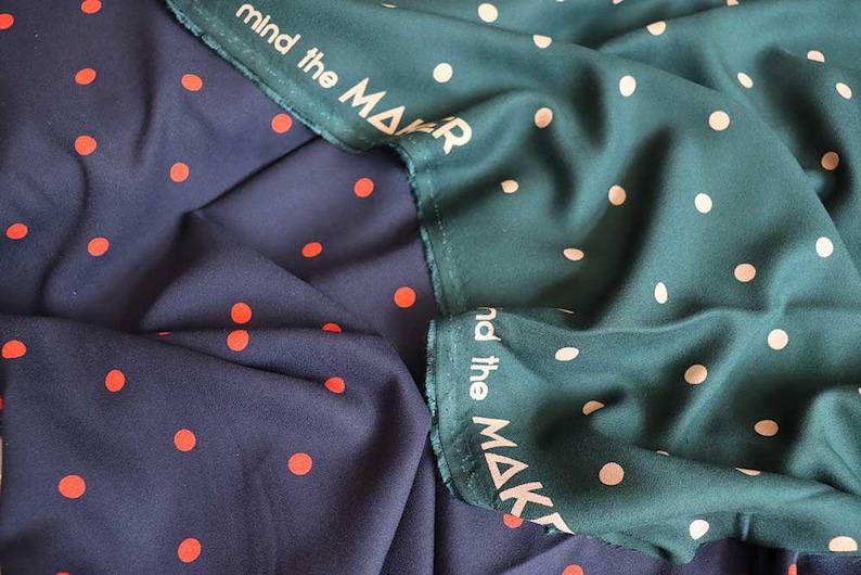 K&ouml;nnte beinhalten: Zwei Stoffe mit Polka-Dot-Muster. Einer ist marineblau mit orangefarbenen Punkten, der andere ist teal mit cremefarbenen Punkten. Der teal Stoff hat den Text "mind the MAKER" am Rand aufgedruckt.