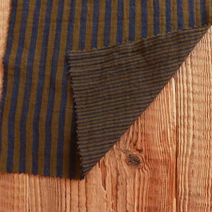 Könnte beinhalten: Zwei Stücke gestreiften Stoffes in Braun und Blau, übereinander gelegt und auf einer Holzoberfläche platziert.