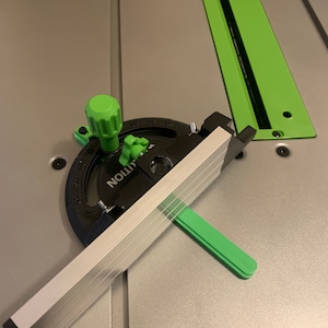 May include: A black and green woodworking tool with a protractor and a sliding ruler. The tool is labeled "UNION" and has markings in degrees.