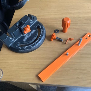 May include: A black and orange woodworking tool with a protractor and a knob. The tool is labelled "Evolution".