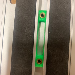 May include: A green level with two gold screws, mounted on a silver track.