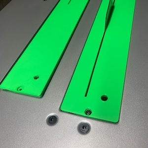 May include: Two green plastic table saw extension wings with black screw holes. The wings are attached to a silver table saw.
