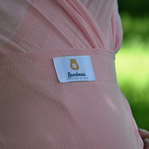 May include: A pink mesh baby wrap with a white label that says "Bambeari Designed by Mom".