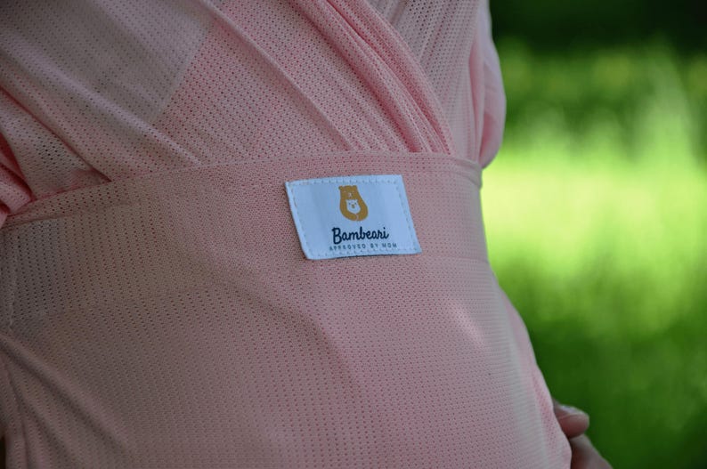 May include: A pink mesh baby wrap with a white label that says "Bambeari Designed by Mom".