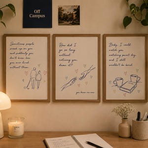 Op de afbeelding: Drie ingelijste wandposters met lichte houten lijsten, elk voorzien van donkerblauwe cursieve tekst en eenvoudige lijntekeningen. De prints tonen romantische citaten, illustraties van twee personen, reikende handen, koffie en een boek, met kleine hartjes.