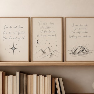 Puede incluir: Tres láminas decorativas verticales enmarcadas con fondo beige claro e ilustraciones en tinta negra. La primera muestra una estrella y el texto "You do not fear. You do not falter. You do not yield." La segunda presenta montañas, una luna creciente y estrellas con el texto "To the stars who listen—and the dreams that are answered." La tercera ilustra una roca entre olas rompientes con el texto "I am the rock against which the surf crashes. Nothing can break me."
