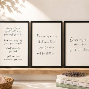 May include: Three rectangular wall art prints in black frames featuring black cursive text on a white background. The first print reads: always throw spilt salt over your left shoulder, keep rosemary by your garden gate, plant lavender for luck, fall in love whenever you can. The second print reads: I dream of a love that even time will lie down and be still for. The third print reads: Curses only have power when you believe them.