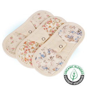 May include: Three floral patterned oven mitts with a beige background and a button on each mitt. The mitts are made with organic blended content.