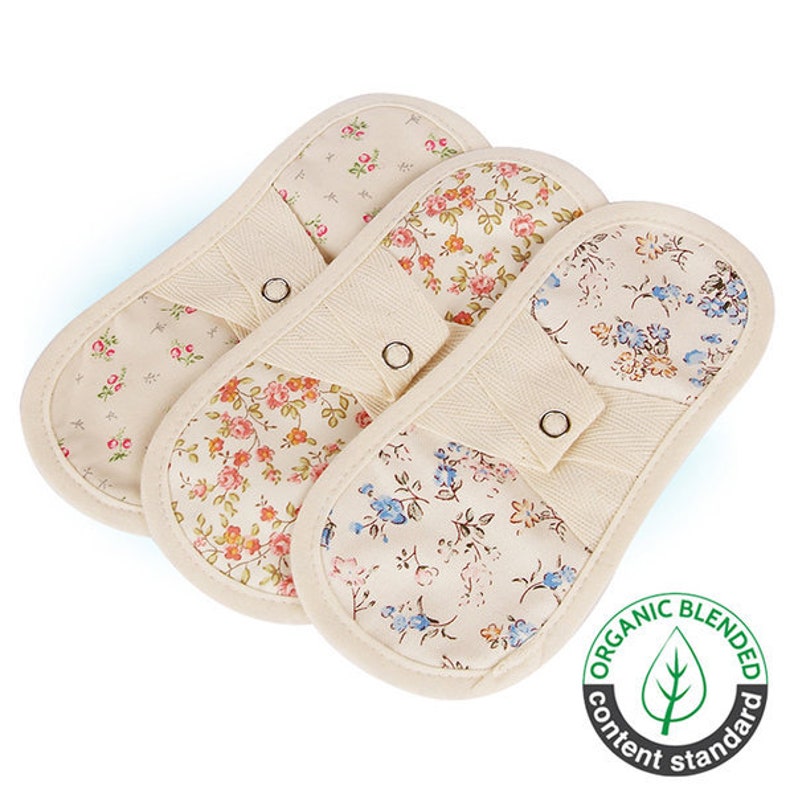 May include: Three floral patterned oven mitts with a beige background and a button on each mitt. The mitts are made with organic blended content.