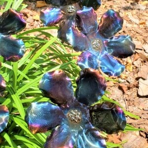 May include: A set of five metal flowers with iridescent blue, purple, and gold hues. The flowers are made of metal and have a realistic appearance.