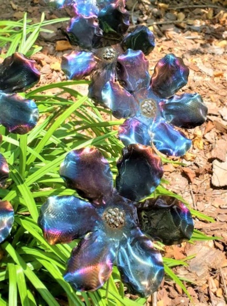 May include: A set of five metal flowers with iridescent blue, purple, and gold hues. The flowers are made of metal and have a realistic appearance.