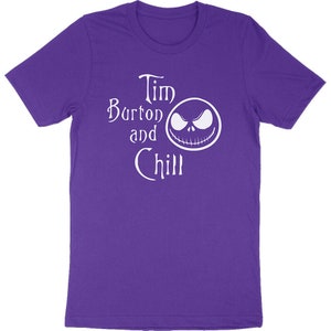 Op de afbeelding: Een paars T-shirt met de witte tekst "Tim Burton and Chill" en een witte afbeelding van een gezicht. Het shirt is gemaakt van een zacht materiaal en heeft korte mouwen.