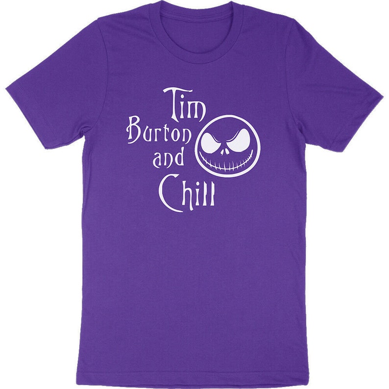 Op de afbeelding: Een paars T-shirt met de witte tekst "Tim Burton and Chill" en een witte afbeelding van een gezicht. Het shirt is gemaakt van een zacht materiaal en heeft korte mouwen.