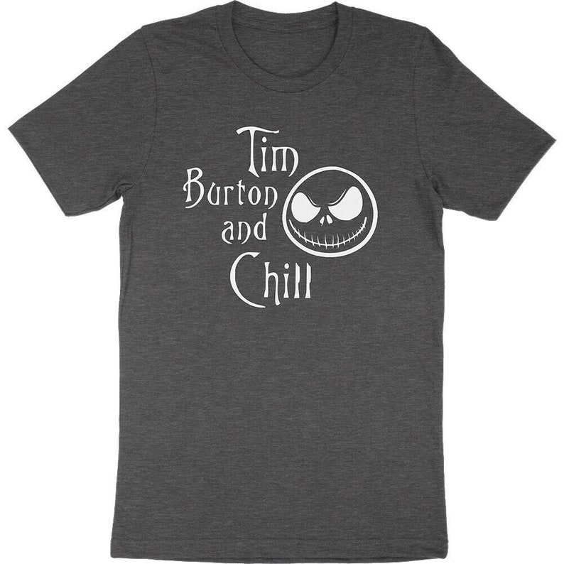 Op de afbeelding: Donkergrijs t-shirt met de witte tekst "Tim Burton and Chill" en een witte afbeelding van een gezicht. Het t-shirt heeft korte mouwen en is gemaakt van een zacht materiaal.