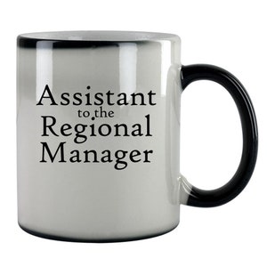 May include: White ceramic coffee mug with a black handle. The mug has black text that reads "Assistant to the Regional Manager".