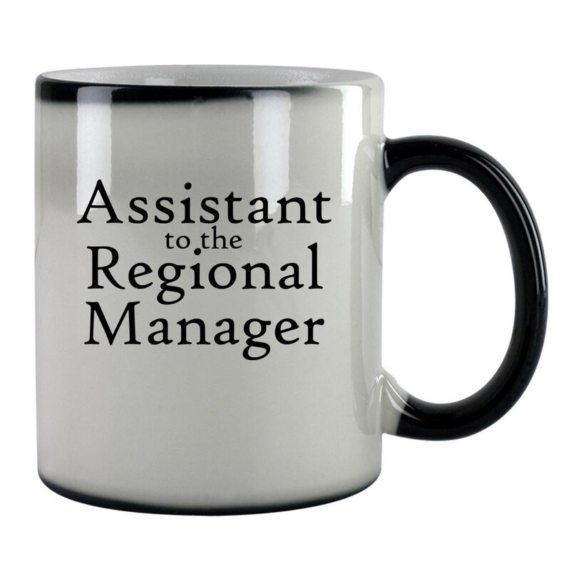 May include: White ceramic coffee mug with a black handle. The mug has black text that reads "Assistant to the Regional Manager".