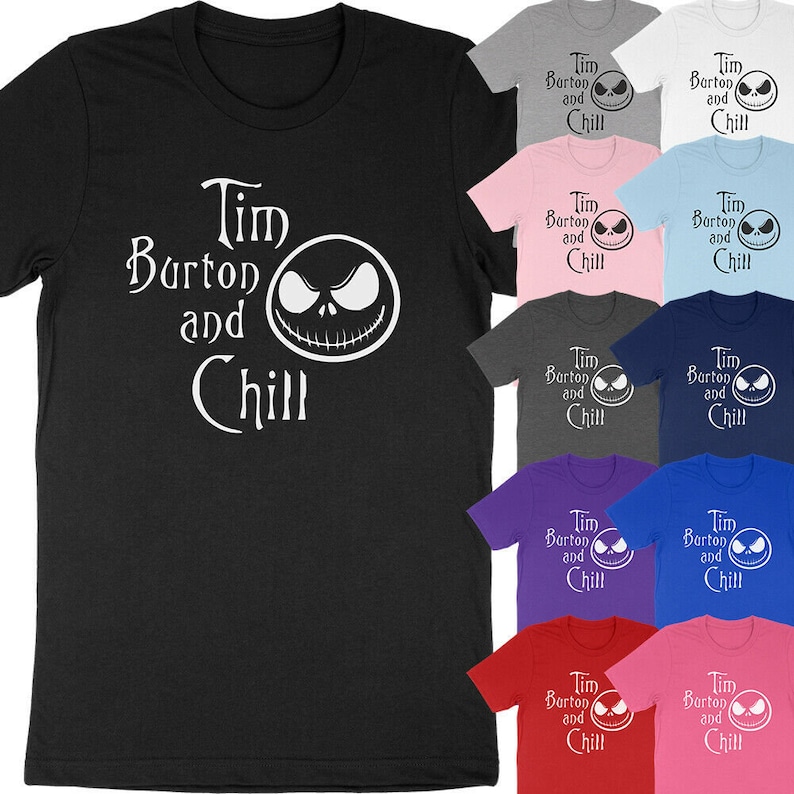 Op de afbeelding: Een zwart t-shirt met de witte tekst "Tim Burton and Chill" en een witte afbeelding van een gezicht. Extra t-shirts in verschillende kleuren, waaronder grijs, roze en blauw, zijn ook zichtbaar.