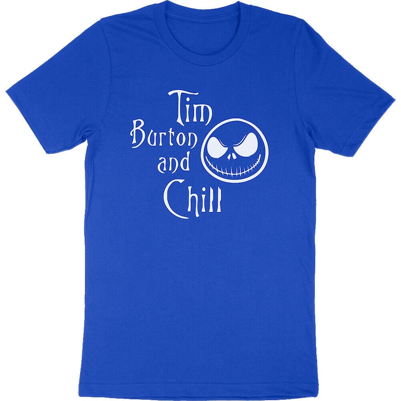 Op de afbeelding: Koningsblauw T-shirt met de witte tekst "Tim Burton and Chill" en een witte afbeelding van een gezicht. Het shirt is gemaakt van een zacht materiaal en heeft korte mouwen.