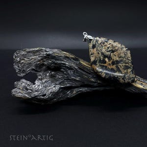 May include: A black and brown stone pendant with a silver bail. The stone has a unique, swirling pattern.