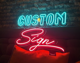 Könnte beinhalten: Ein zweistufiges Neonschild mit dem Wort CUSTOM in hellen cyanfarbenen Blockbuchstaben, das über dem Wort Sign in einer fließenden roten Schreibschrift angebracht ist. Das Schild ist auf einer transparenten Acrylplatte montiert und leuchtet.