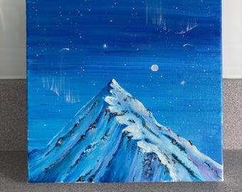 May include: A square canvas painting depicts a snow-capped mountain peak under a deep blue night sky. The scene features a bright moon, numerous white stars, and faint streaks of light resembling the aurora borealis above the summit.