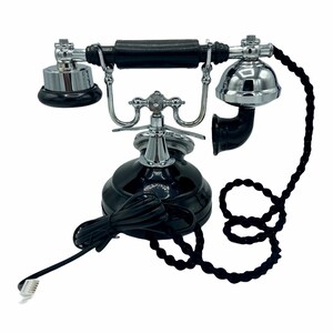 Pode incluir: Um telefone rotativo preto com base e auricular cromados. O telefone tem um cabo enrolado e um cabo preto com um plugue.