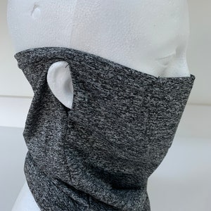May include: Gray and black patterned neck gaiter with a small hole on the side for the ear. The gaiter is made of a soft, stretchy fabric.