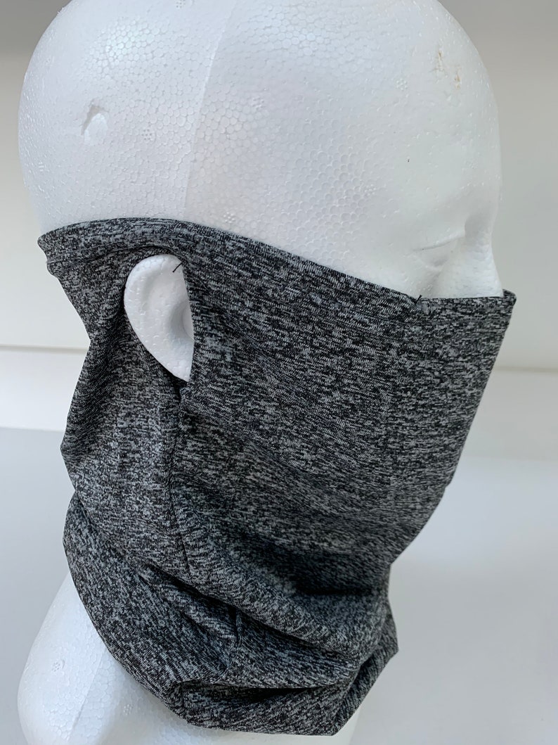 May include: Gray and black patterned neck gaiter with a small hole on the side for the ear. The gaiter is made of a soft, stretchy fabric.