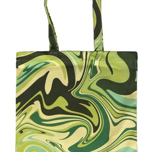 May include: A green and black tote bag with a swirling, marbled pattern. The bag has a rectangular shape with a matching handle. The design features shades of green, black, and cream, creating a psychedelic effect. The bag is made of fabric.