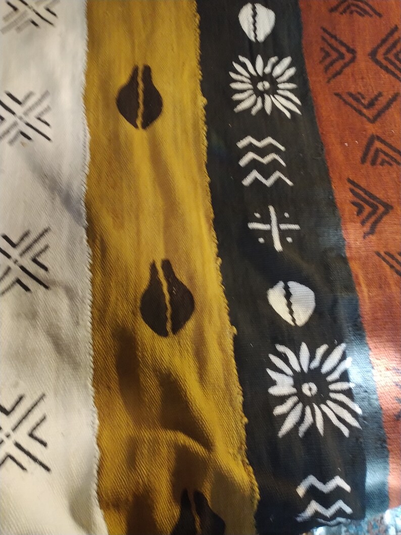 May include: A close-up of a woven fabric with a colorful striped pattern. The fabric features geometric shapes and designs in black, white, brown, yellow, and orange.
