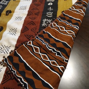 May include: A brown and white patterned throw blanket with a fringe border. The blanket is folded in half and the pattern is visible on both sides.