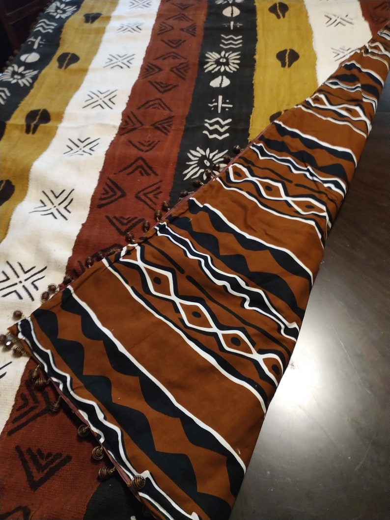 May include: A brown and white patterned throw blanket with a fringe border. The blanket is folded in half and the pattern is visible on both sides.