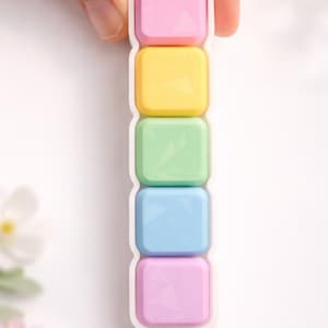 May include: A white ceramic mug with a black handle and the text "But First, Coffee" in a bold, black font. The mug is set against a blurred background, suggesting a cozy setting.