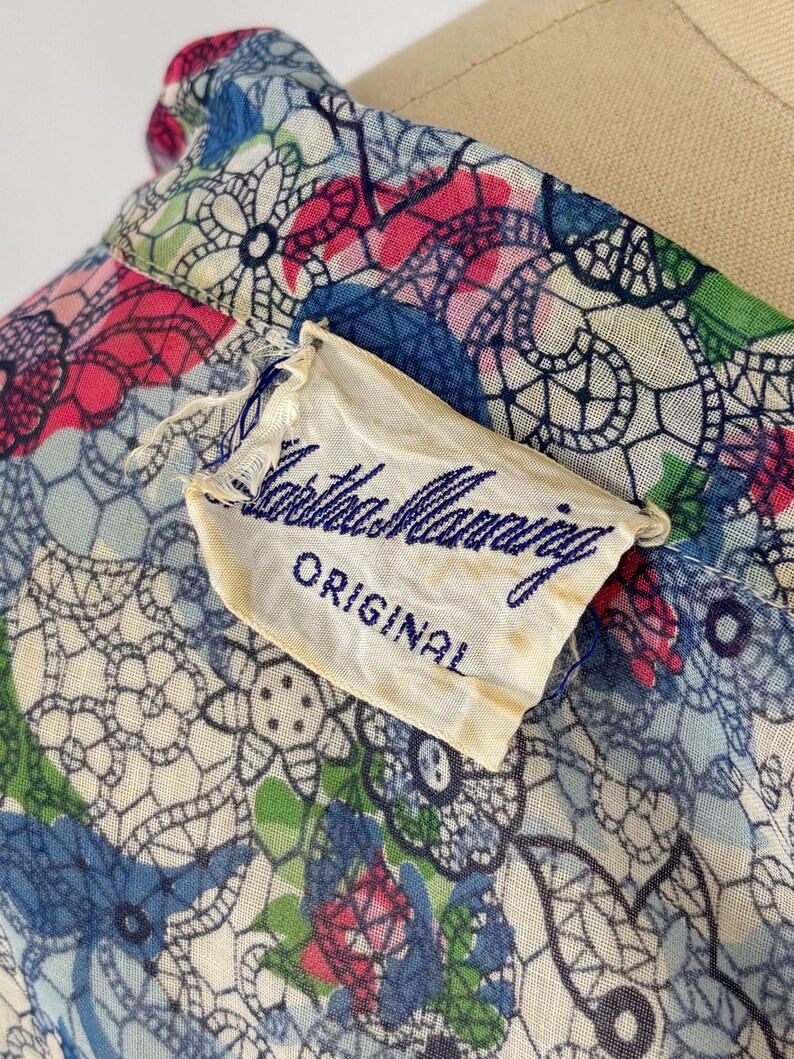 Close of of the label of the 1940's shirtwaist dress. The label reads "Martha Manning ORIGINAL" in blue script.