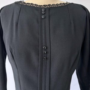 Close-up of the neckline. There are darts and princess seams leading down to the bust. The lace trim is delicate around the neckline.