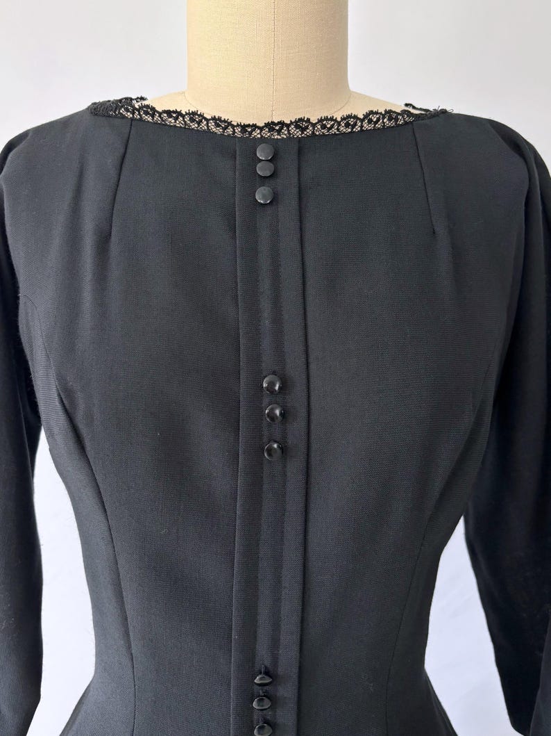 Close-up of the neckline. There are darts and princess seams leading down to the bust. The lace trim is delicate around the neckline.