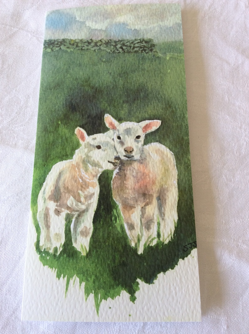 May include: Watercolor painting of two white lambs in a green field. The lambs are facing each other and appear to be nuzzling. The background is a green field with a stone wall and a cloudy sky.