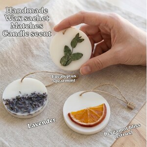 a hand holding a handmade wax sachet with various scents, including lavender, eucalyptus, and citrus.