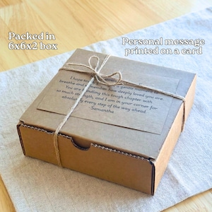 A cardboard box with a personal message printed on a card tied with twine, placed on a wooden surface.