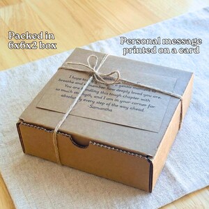 A cardboard box with a personal message printed on a card tied with twine, placed on a wooden surface.