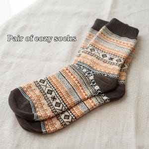 A pair of cozy socks with a patterned design, resting on a light-colored fabric.