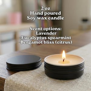 A hand poured soy wax candle with a lit flame, placed on a wooden surface.