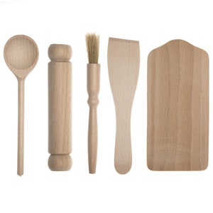 May include: A set of five wooden kitchen utensils, including a spoon, rolling pin, pastry brush, spatula, and a small chopping board. The items are made of light-coloured wood and are arranged against a white background.