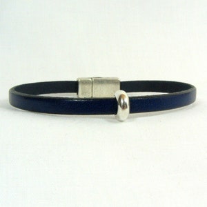 May include: A dark blue leather bracelet with a silver magnetic clasp and a silver bead.