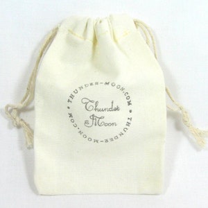 May include: A white cotton drawstring bag with a silver logo that reads "Thunder & Moon.com".