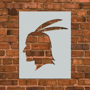 May include: A stencil of a Native American profile with a feather headdress. The stencil is made of white plastic and is designed for use with paint.